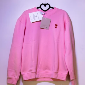 Rosa sweatshirt från Ami Paris - Säljer en Helt ny Ami Paris Sweatshirt med ett märke på bröstet. Tröjan har långa ärmar och en klassisk passform. Kom med frågor och bud!😊 Obs den ser större ut på bild än i verkligheten