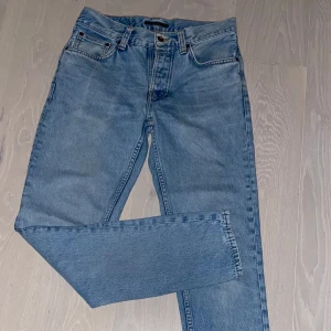 Blå jeans från Nudie Jeans - Snygga blå jeans från Nudie Jeans i en klassisk straight fit. De har en knappgylf och femficksdesign. Perfekta för en avslappnad stil. Nudie Steady Eddie II är ett par jeans med normal passform, avsmalnande ben och noggrant utformad sliten tvätt. Jeansen har smal benöppning, knappgylf och tobakstråd i sömmarna. (Inga returer)