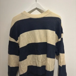 Randig tröja från H&M Divided - Säljer en randig tröja från H&M Divided i beige och blå. Tröjan har långa ärmar och en rund halsringning. Sjukt snygg
