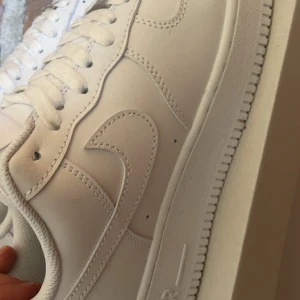 Vita Nike Air Force sneakers - Säljer ett par klassiska vita Nike Air Force sneakers. Skorna har en stilren design med snörning och är tillverkade i syntetmaterial. Perfekta för en casual look.