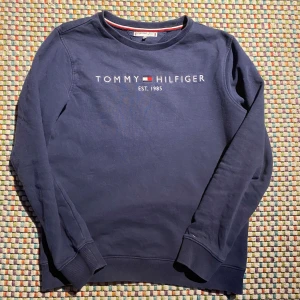 Blå tröja från Tommy Hilfiger - Säljer nu denna snygga tröja från tommy hilfiger👔. Färgen är blå och den är gjord av 100% bomull🐑skulle älska att höra från dig vid minsta tanke på att köpa✌️Det står 164 på etiketten, men passar perfekt som en XS👑