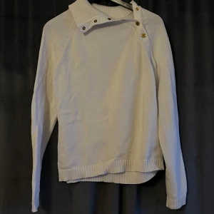 Vit stickad tröja från Ralph Lauren - Säljer en vit stickad tröja från Ralph Lauren. Tröjan har en unik knapprad med guldknappar och är i ganska bra skick. Kontakta gärna vid frågor☺️