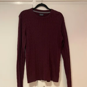 Vinröd tröja från Jack & Jones - Snygg vinröd tröja från Jack & Jones med kabelstickat mönster. Perfekt för kyligare dagar med sin stilrena design och bekväma passform.