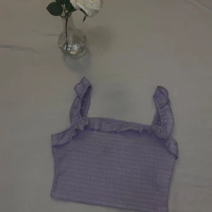 Lila ribbad linnetopp med volangdetaljer - Söt lila ribbad linnetopp med volangdetaljer vid axelbanden i storlek XS (EU:34). Perfekt för sommaren 💞☀️