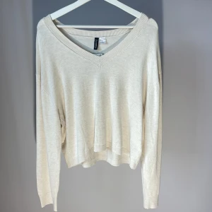 Beige tröja från H&M - Säljer en stilren beige tröja från Gina Tricot med v-ringad hals och långa ärmar. Perfekt för en avslappnad look. Tröjan har en mjuk och bekväm passform.