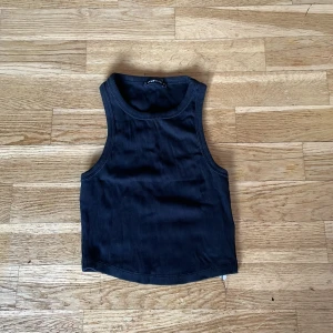 Svart ribbad linnetopp från FB Sister - Säljer en snygg svart ribbad linnetopp från FB Sister. Toppen är i mycket bra skick och i storlek S. Perfekt för en stilren look med sin ärmlösa design och rundade hals. Passar utmärkt till både jeans och kjol. Ett måste i garderoben för alla som älskar enkel och trendig stil.