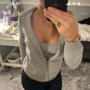 Grå hoodie med dragkedja - Säljer en grå hoodie med dragkedja framtill. Den har långa ärmar och en bekväm passform, perfekt för en avslappnad stil. Huvan ger extra mysfaktor och den neutrala färgen gör den lätt att matcha med andra plagg.