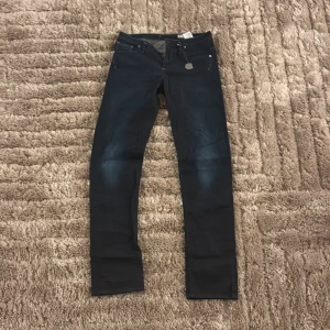 Mörkblå jeans från G-Star - Snygga mörkblå jeans från G-Star med en klassisk femficksdesign. Jeansen har en dragkedja och knapp framtill samt en liten metallbricka med G-Star-logga. Perfekta för en stilren look. Jeansen är i underbart skick och har använts väldigt sällan.