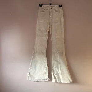 Vita bootcut jeans - Snygga vita bootcut jeans med hög midja och klassisk femficksdesign. Perfekta för en stilren look. De har en knapp och dragkedja framtill.