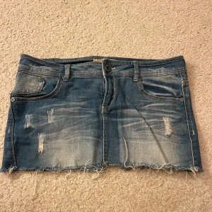 Blå jeanskjol från bershka - Snygg blå jeanskjol från bershka med slitna detaljer och fransig nederkant. Kjolen har klassisk femficksdesign. Midjemått: 41cm rakt över. Längd: 26cm. Använd gärna köp nu💕💕