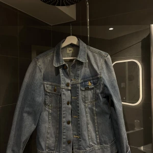 Blå jeansjacka från Lee - Snygg blå jeansjacka från Lee i storlek M. Klassisk design med knappar framtill och två bröstfickor. Perfekt för en avslappnad stil.