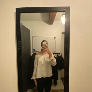 Vit offshoulder blus - Säljer en stilren vit offshoulder blus med långa ärmar. Perfekt för en elegant och avslappnad look. Blusen har en luftig passform och är lätt att matcha med olika outfits.