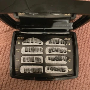 Svart förpackning med magnetiska lösögonfransar - Säljer en elegant svart förpackning med magnetiska lösögonfransar. Inkluderar flera par för både övre och nedre fransraden. Perfekt för att skapa en dramatisk look utan lim. En ögonfransböjare i guld ingår också för att ge extra lyft.