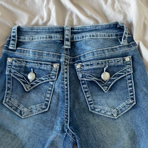 Blå jeans från Fire & Rain - Snygga blå jeans från Fire & Rain med dekorativa bakfickor och kontrastsömmar. De har en klassisk femficksdesign och en knappgylf. Perfekta för en avslappnad stil.