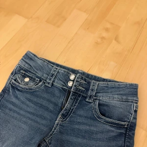 Blå jeans med knappar - Snygga blå jeans med låg midja och bootcut från Gina Young i tall. Har använt jeansen en gång så de är som nya! 