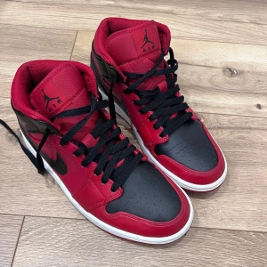 Nike Air Jordans 1 i rött och svart - Snygga Nike Air Jordans 1 i en klassisk röd och svart färgkombination. Skorna har en hög modell med snörning och den ikoniska Air Jordan-loggan på sidan. Perfekta för dig som vill ha en stilren och sportig look.De är toppen skick ingen crease på dom.De är storlek 42.Köpt för 1500 