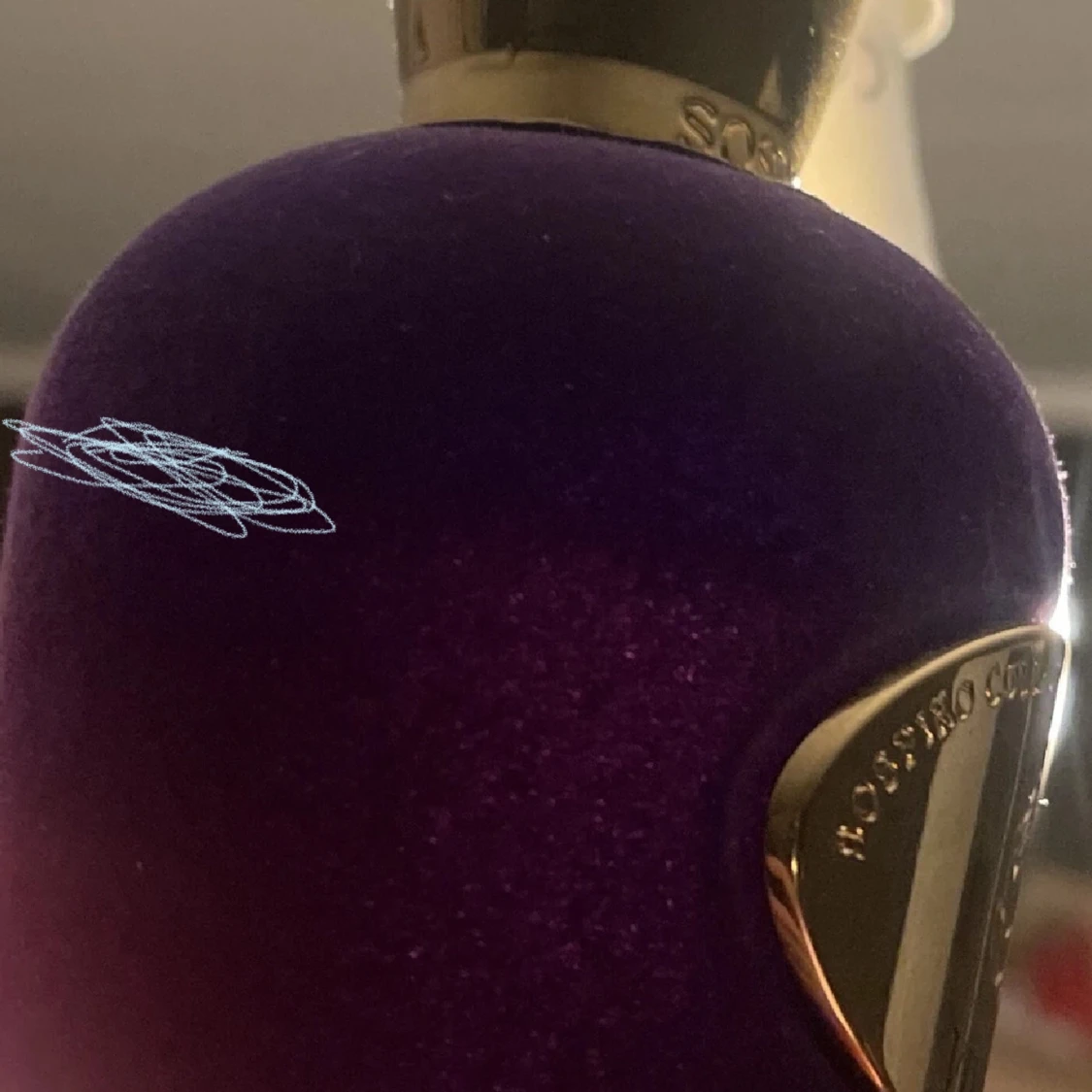 Lila parfymflaska med gulddetaljer