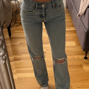 Blå jeans med slitningar - Säljer ett par blå jeans med slitningar på knäna ifrån Zara då de aldrig kommit till användning. Jeansen är i storlek 34 men kan även passa storlek 36. De är även lågmidjade. Kan skicka fler bilder vid önskemål💞