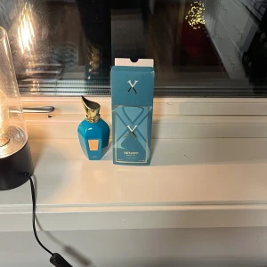 Xerjof erba pura - Säljer en elegant blå parfymflaska från Xerjoff med en gyllene kork. Förpackningen är också blå med en stilren design. Perfekt för den som söker en lyxig doftupplevelse. Använd enstaka gånger