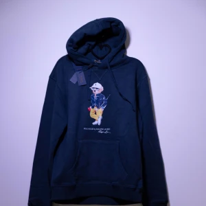 Ralph Lauren Hoodie - Helt ny Ralph Lauren Hoodie med en ikonisk nallebrodyr på framsidan. Hoodien har en klassisk passform med justerbar huva och en praktisk magficka. Perfekt för en avslappnad stil. Fler storlekar finns i min profil😊