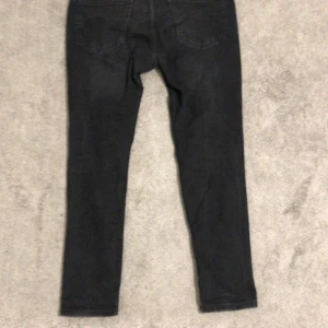 Svarta jeansbyxor - Snygga svarta jeansbyxor med en tight passform. De har en klassisk design med fem fickor och är perfekta för en stilren look. Passar bra till både vardag och mer uppklädda tillfällen.