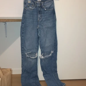 Blå jeans från 157 Boulevard - Snygga blå jeans från 157 Boulevard med slitna detaljer på knäna. De har en klassisk femficksdesign och hög midja. Perfekta för en avslappnad stil. Jättebekväma och stiliga. Bootcut