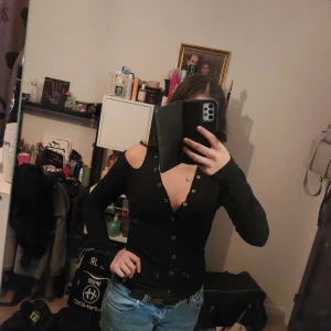 Svart offshoulder kofta - Snygg svart kofta med offshoulder-design och knappar framtill. Perfekt för en stilren look.