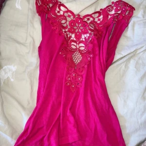 Rosa topp med spetsdetaljer från Dolce & Gabbana - Säljer en snygg rosa topp från Dolce & Gabbana med spets på ryggen. Toppen har en figurnära passform. Köpt för flera år sedan , men den är i superfint skick förutom att några få stenar ramlat av (se sista bild) men inget man tänker på när man har den på sig. Knappt sett nån annan som haft en sån tröja så väldigt unik & cool!