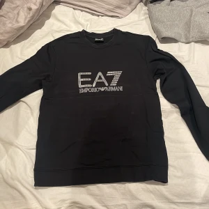 Svart tröja från Emporio Armani - Snygg svart tröja från Emporio Armani med EA7-logga på bröstet. Perfekt för en stilren look.