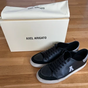 Svarta skor från Axel Arigato - Snygga svarta skor från Axel Arigato med en vit sula och ett 'A' på sidan. Storlek 42 herr. Skorna har snörning och kommer med originalförpackning och dustbag. I använt men bra skick.