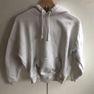 Vit hoodie med ficka - Säljer en klassisk vit hoodie med justerbar dragsko i huvan. Perfekt för en avslappnad stil. Passar bra till både jeans och mjukisbyxor.
