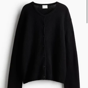 Svart kofta från H&M - Snygg och stilren svart kofta från H&M med knappar framtill. Perfekt för lager-på-lager under kyligare dagar. Den har långa ärmar och en klassisk design som passar till det mesta. Är i storlek XL men på sitter den som en S 