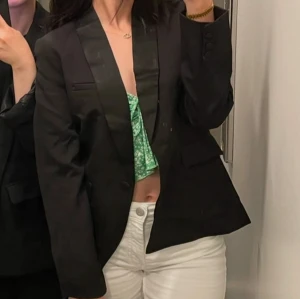 Svart kavaj från New Look - Snygg svart kavaj från New Look med en elegant satinliknande krage. Perfekt för att ge en stilren touch till din outfit. Kavajen har en knapp framtill och fickdetaljer på sidorna. Jag är 166 long och bär på mig storlek 36 , Kontakta mig vid fler frågor ✨✨