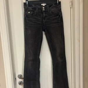 Svarta bootcut jeans från Gina Tricot - Snygga svarta bootcut jeans från Gina Young med dubbla knappar i midjan. Perfekta för en stilren look med en klassisk passform. Jeansen har en mörk tvätt och vita sömmar som ger en cool kontrast. Storlek 164, finns inga tydliga teckna på användning. Använda max 10 gånger 🩷🩷BOOTCUT LÅGMIDJADE
