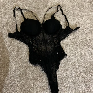 Svart spetskorsett - Elegant svart korsett med spetsdetaljer och justerbara axelband. Designen är både sexig och sofistikerad, perfekt för speciella tillfällen.