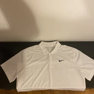 Vit pikétröja Nike - Säljer en vit kortärmad pikétröja från Nike. Perfekt till golfbanan eller annan sport, då den är snygg, tunn och luftig.