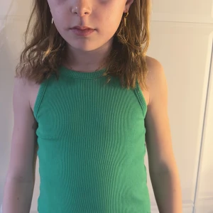 Grön ribbad linnetopp - Snygg grön ribbad linnetopp med breda axelband. Perfekt för varma dagar och enkel att matcha med olika outfits.