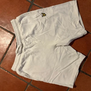 Vita shorts från Lyle & Scott - Snygga vita shorts från Lyle & Scott med elastisk midja och en liten broderad logga på framsidan. Perfekta för en avslappnad stil under varma dagar. De har en bakficka för extra funktionalitet.