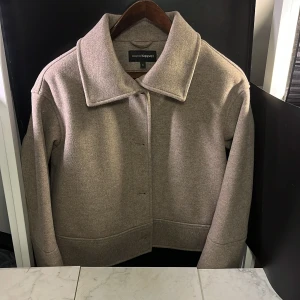 Beige kappa från KappAhl - Snygg beige kappa från KappAhl i storlek S. Jackan har en klassisk krage och knäppning framtill. Perfekt för höst och vår, den är i ett mycket fint skick och mycket skönt material. Hör av er vid minsta fundering🙌
