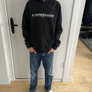 Svart hoodie til barn från Rascals - Säljer en svart Rascals huvtröja i storlek S (passar ca 160–170 cm). Tröjan har en känguruficka, justerbar huva och texten “N. Copenhagen” tryckt på bröstet. Mjuk bomullsblandning som är perfekt för en avslappnad stil. Modellen på bilderna är 160 cm lång, 12 år gammal, och har en smal/normal kroppsbyggnad.  Skick: Bra begagnat skick, med minimala tecken på användning.  Nypris: 600 SEK