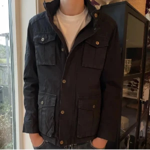 Svart Filde jacka - Snygg svart jacka med knappar och flera fickor framtill. Jackan har en klassisk design med krage och långa ärmar. Perfekt för en stilren look.