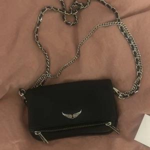 Svart axelväska från Zadig & Voltaire - Snygg svart axelväska i grained leather från Zadig & Voltaire. Har använt den MAX 10 ggr och den är helt som ny. Det är den lilla modellen och nypris ligger runt 2700. Båda kedjorna och väskan är i superbra skick och det finns inga som helst skråmor eller skador! Skriv för egna bilder! Självklart äkta, lappar mm medföljer!
