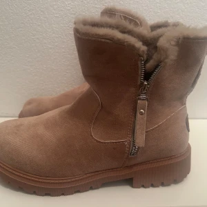 Helt Ny!! Oanvända Beige boots ( storlek 38) med foder och dragkedja - Helt ny Snygga beige boots i mocka med mjukt foder och praktisk dragkedja på sidan. Perfekta för kyliga dagar med sin robusta sula och stilrena design.storlek 38.