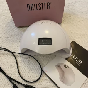 Nagellampa/Uv-lampa  från Nailster - Säljer en vit nagellampa från Nailster med digital display och flera timerinställningar. Perfekt för att härda gelnagellack och gelér snabbt och effektivt. Inkluderar strömkabel och originalförpackning. Den är använd ett fåtal gånger men har några  FÅ gelllacks fläckar.🤗❣️
