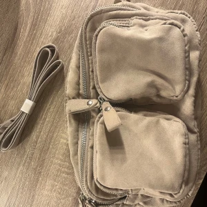 Beige axelväska med dragkedjor - Snygg beige axelväska med flera dragkedjor och praktiska fack. Tillverkad i ett mjukt material. Perfekt för att hålla ordning på dina saker då den är väldigt rymlig. Från Gina i ett använt skick🤍