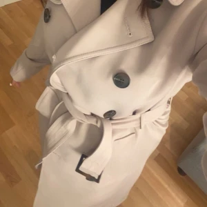 Beige trenchcoat med bälte - Snygg beige coat, aldrig använt. Kan mötas eller fraktas. köpt för 700kr