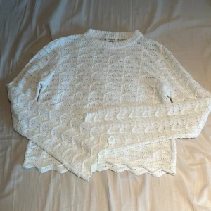 Vit stickad tröja från Kappahl - Säljer en vit stickad tröja från Kappahl med ett fint vågigt mönster. Tröjan har långa ärmar och en rund halsringning. Perfekt för kyligare dagar!