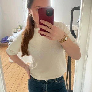 Cremevit stickad tröja/t-shirt/topp - Säljer en stilren vit stickad tröja med korta ärmar. Perfekt för en avslappnad look. Tröjan har en ribbad kant vid halsen och ärmarna. Observera att halskragen är lite ojämn❣️❣️onesize men passar mig som har xs/s kanske passar m med❣️