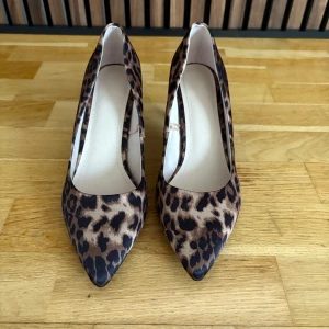 Leopardmönstrade pumps med spetsig tå - Snygga pumps med leopardmönster och spetsig tå. Perfekta för att ge en djärv touch till din outfit. Klackarna ger extra höjd och stil. Aldrig använda.