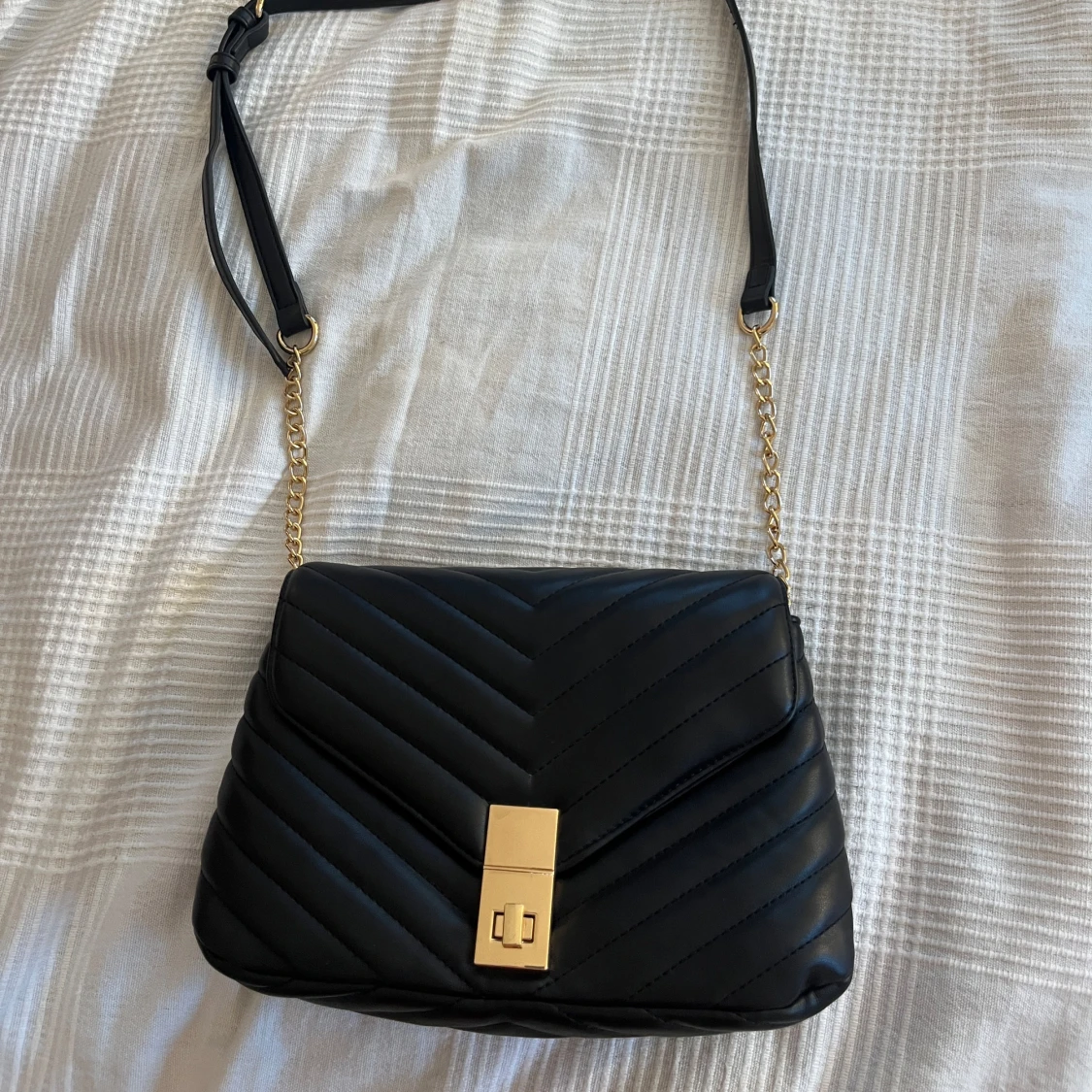 Svart quiltad axelväska med gulddetaljer